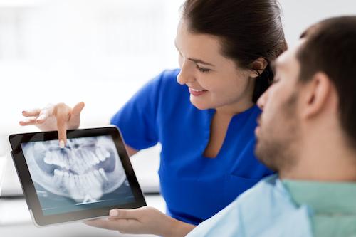 dentist with dental patient showing x-ray | tooth extraction farmington hills mi