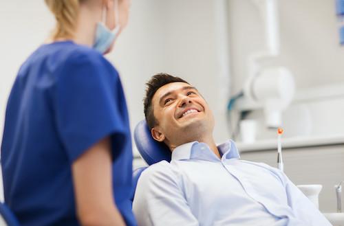 man sitting in dentist exam chair smiling | farmington hills mi dentist