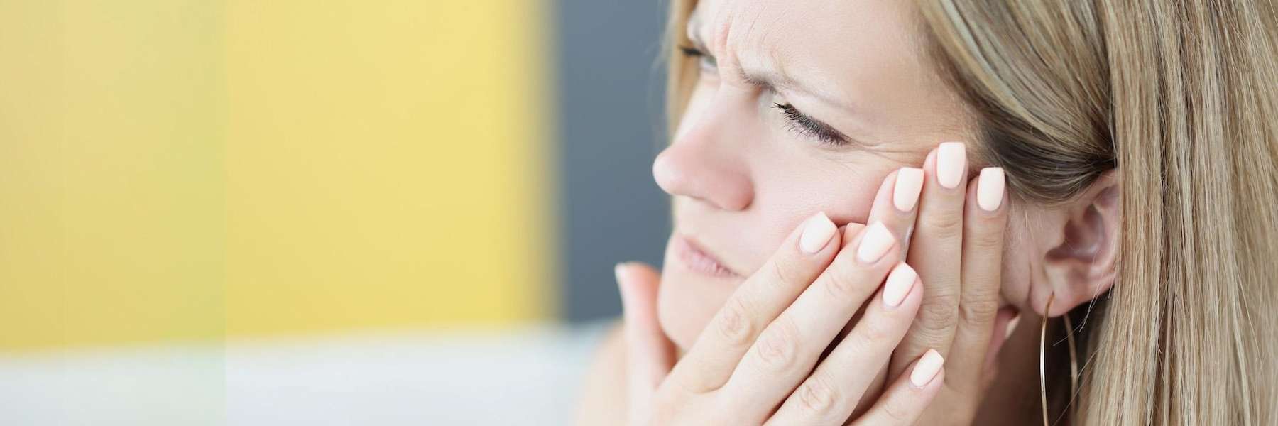 farmington hills woman holding her jaw from tooth pain