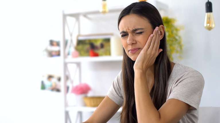 woman holding jaw from infected too pain