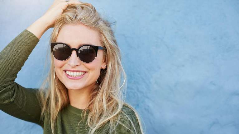 woman with black glasses smiling | dentist farmington hills mi