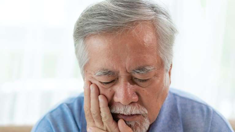 man holding jaw from infected tooth pain before a root canal
