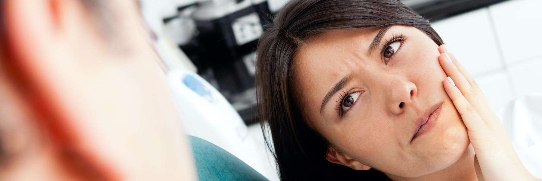 woman holding jaw from tooth pain before a root canal in farmington hills