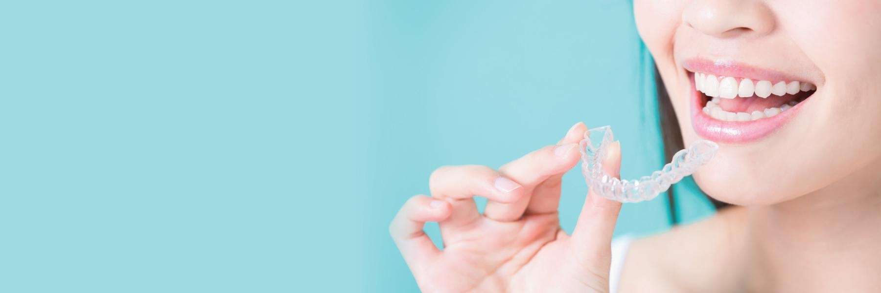 woman holding clear plastic aligner in farmington hills