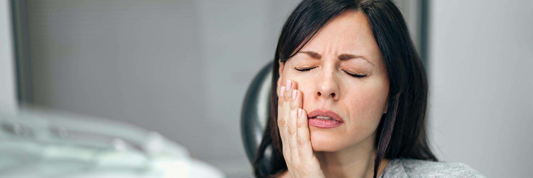 woman in pain holding jaw | root canals farmington hills mi
