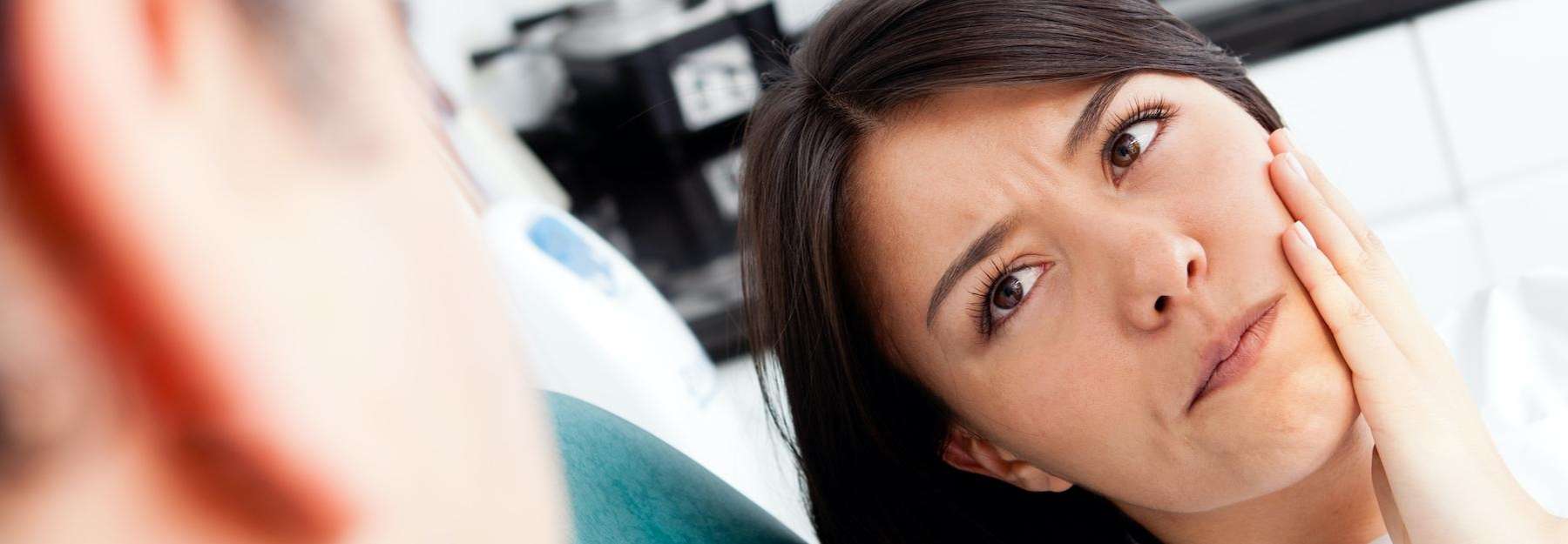 woman in pain holding jaw | emergency dentist farmington hills mi